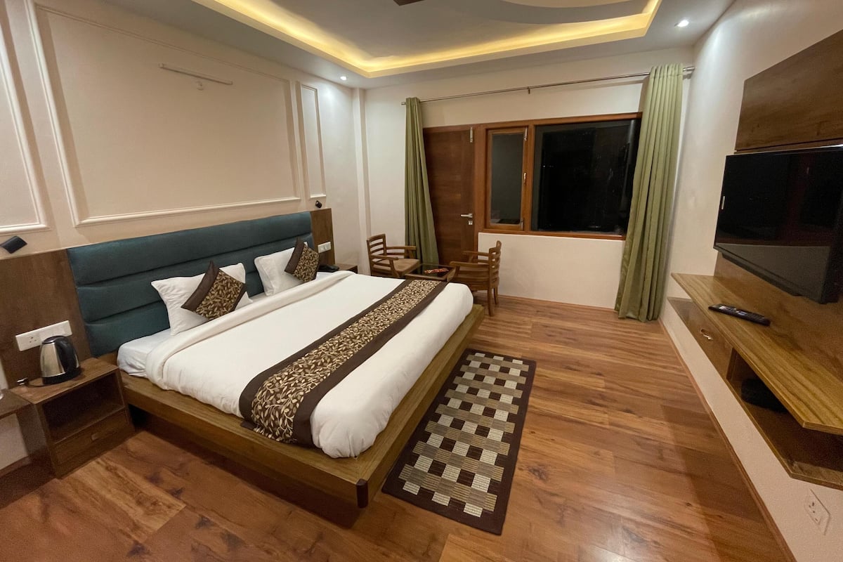 Una habitación de hotel moderna con una cama grande, televisión, escritorio y ventana con cortinas.