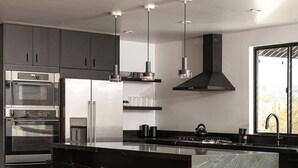 Une cuisine moderne dotée d’un îlot central, de tabourets de bar et d’appareils électroménagers intégrés.