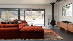 Un salon moderne avec un canapé d’angle, une cheminée et de grandes fenêtres donnant sur le désert.