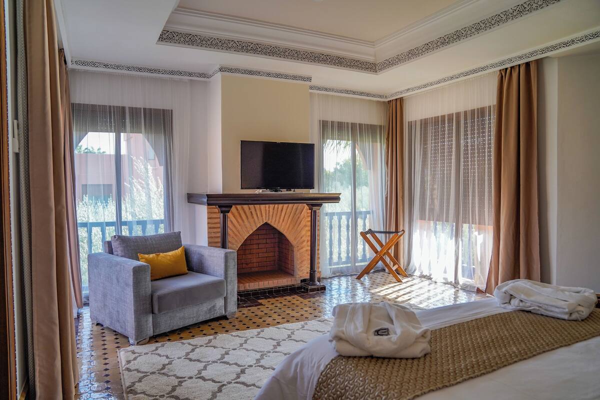 A hotel room with a fireplace, a sofa, a TV, and a bed.