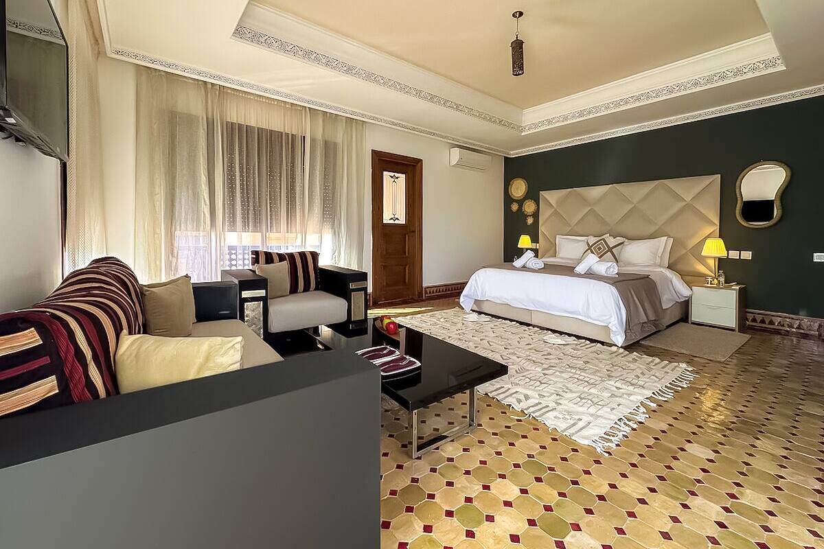 A hotel room with a bed, two sofas, a coffee table, and a patterned floor.