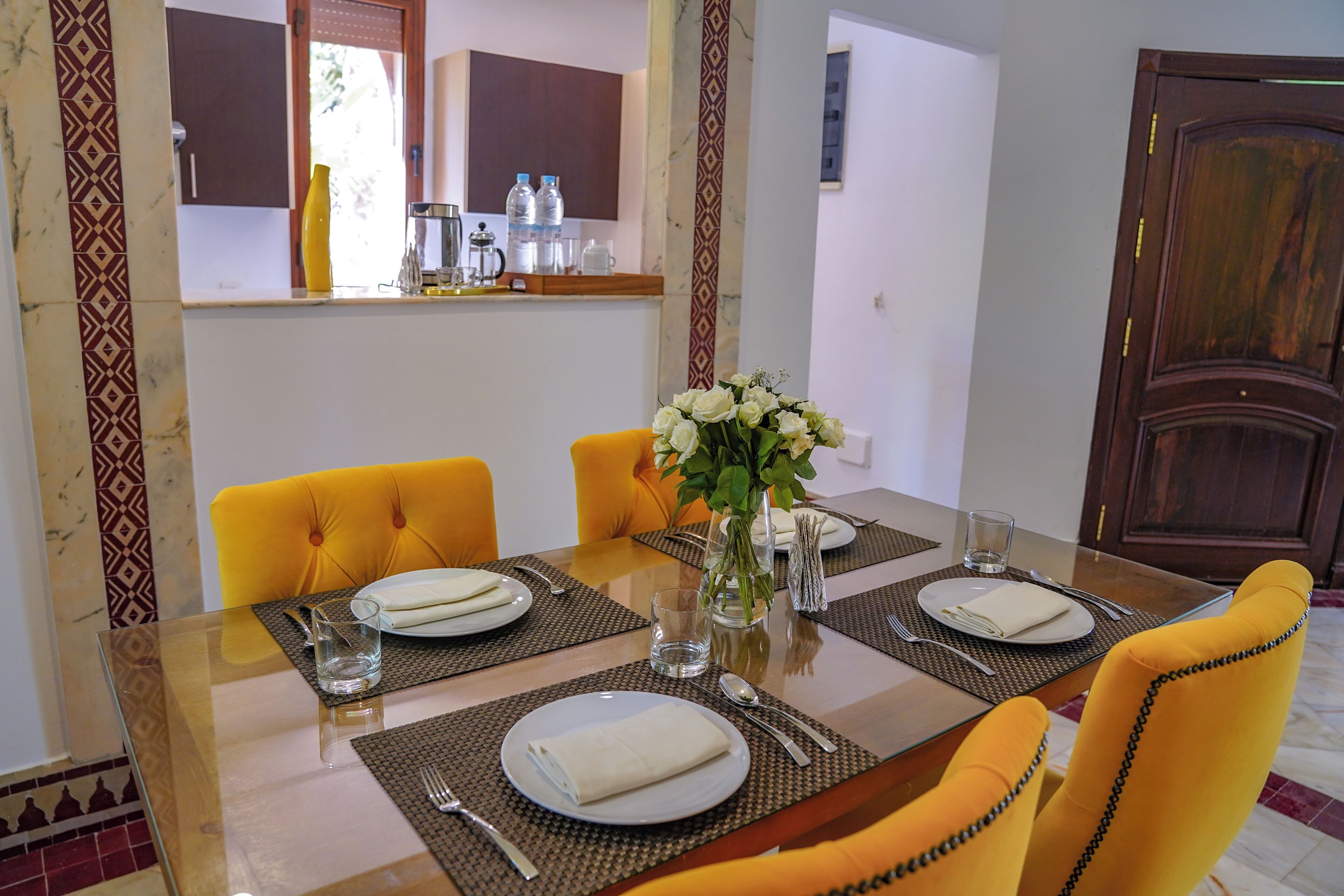 A dining table set with plates, cutlery, and a vase of flowers.