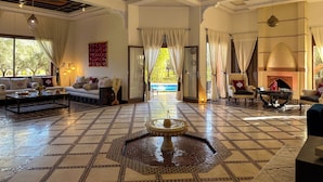 A spacious living area with a large window, a sofa set, a coffee table, and a decorative fountain. - Palais Volteras (Marrakech)