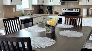 Eine moderne Küche mit weißen Schränken, einer zentralen Kochinsel und einem Essbereich mit einem dunkelholztisch und Stühlen.