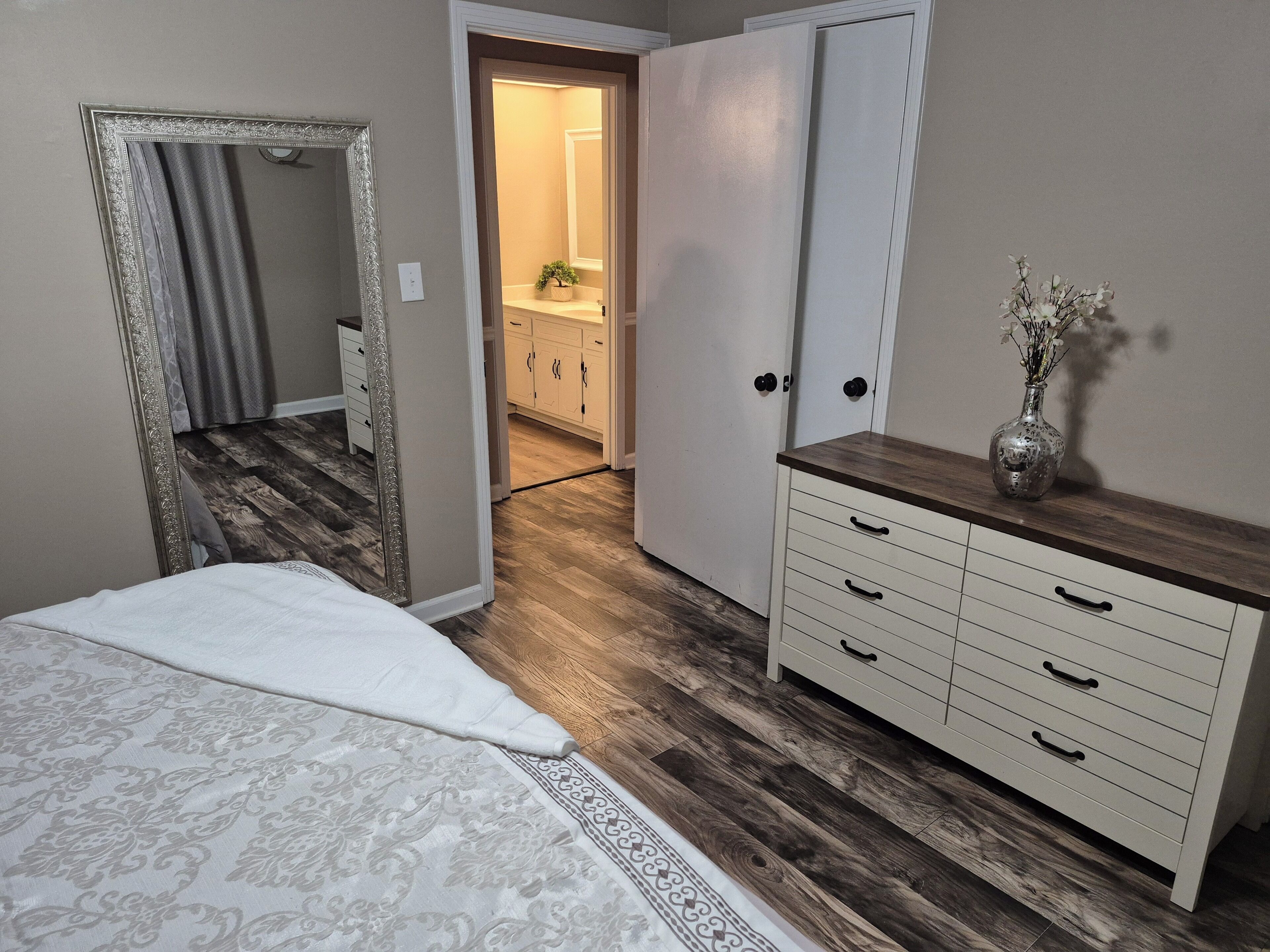 Un dormitorio con cama, cómoda y espejo.