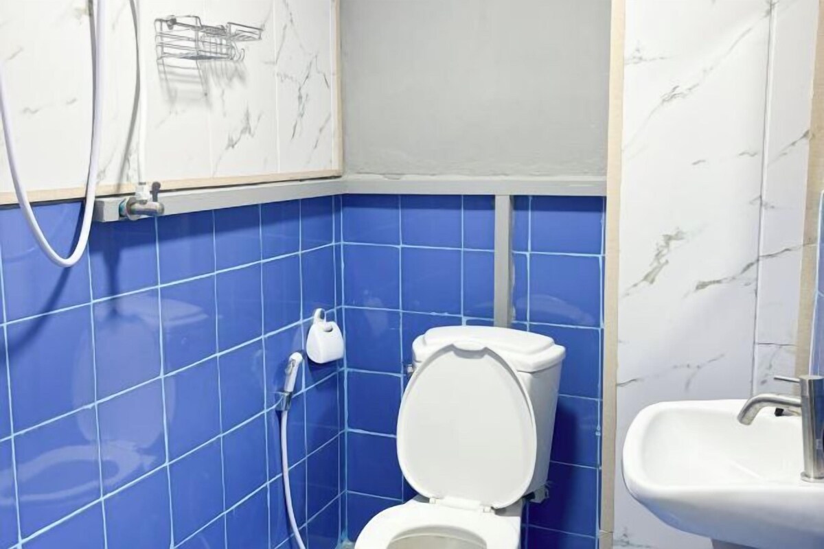 Une salle de bain avec des carreaux bleus, des toilettes blanches, un lavabo et une douche.