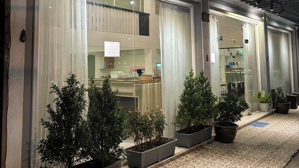Een modern gebouw met grote ramen en een overdekt terras met plantenpotten.