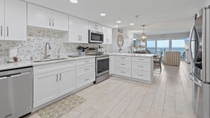 A modern kitchen with white cabinets, stainless steel appliances, and a view to the outside.