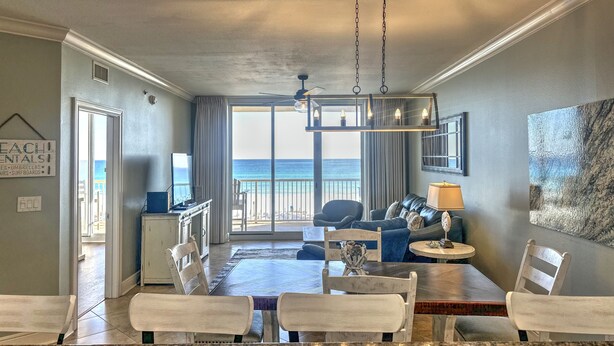 A spacious living area with a dining table, chairs, a sofa, and a view of the ocean.