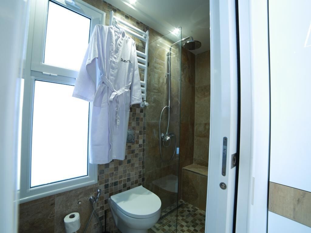A bathroom with a toilet, a shower, and a window.