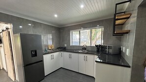 Una cocina moderna con baldosas grises, electrodomésticos de acero inoxidable y un ventanal que aporta luz natural.