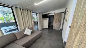 Una sala de estar moderna con un sofá seccional, un comedor y una cocina al fondo.