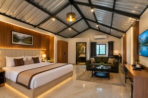 A modern hotel room with a large bed, a sofa, a coffee table, and a TV. - deora resort and hotel (Jodhpur)