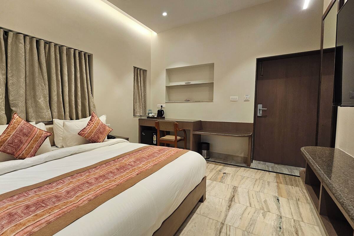 Habitación de hotel con una cama grande, un escritorio, una silla y un armario.