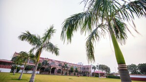 Un cortile con palme e un edificio con archi e un tetto rosso.