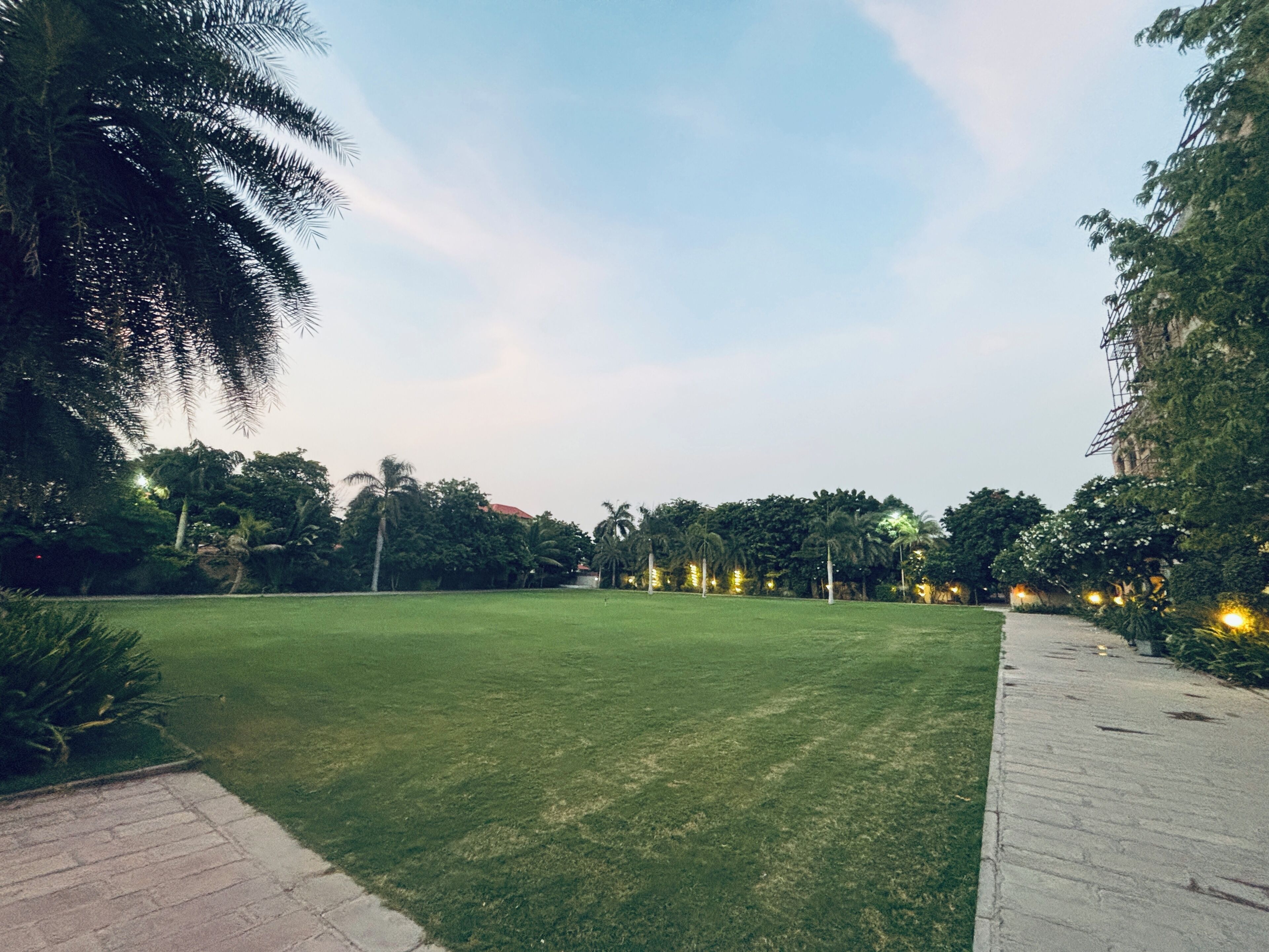A grassy park area with trees and a paved walkway.