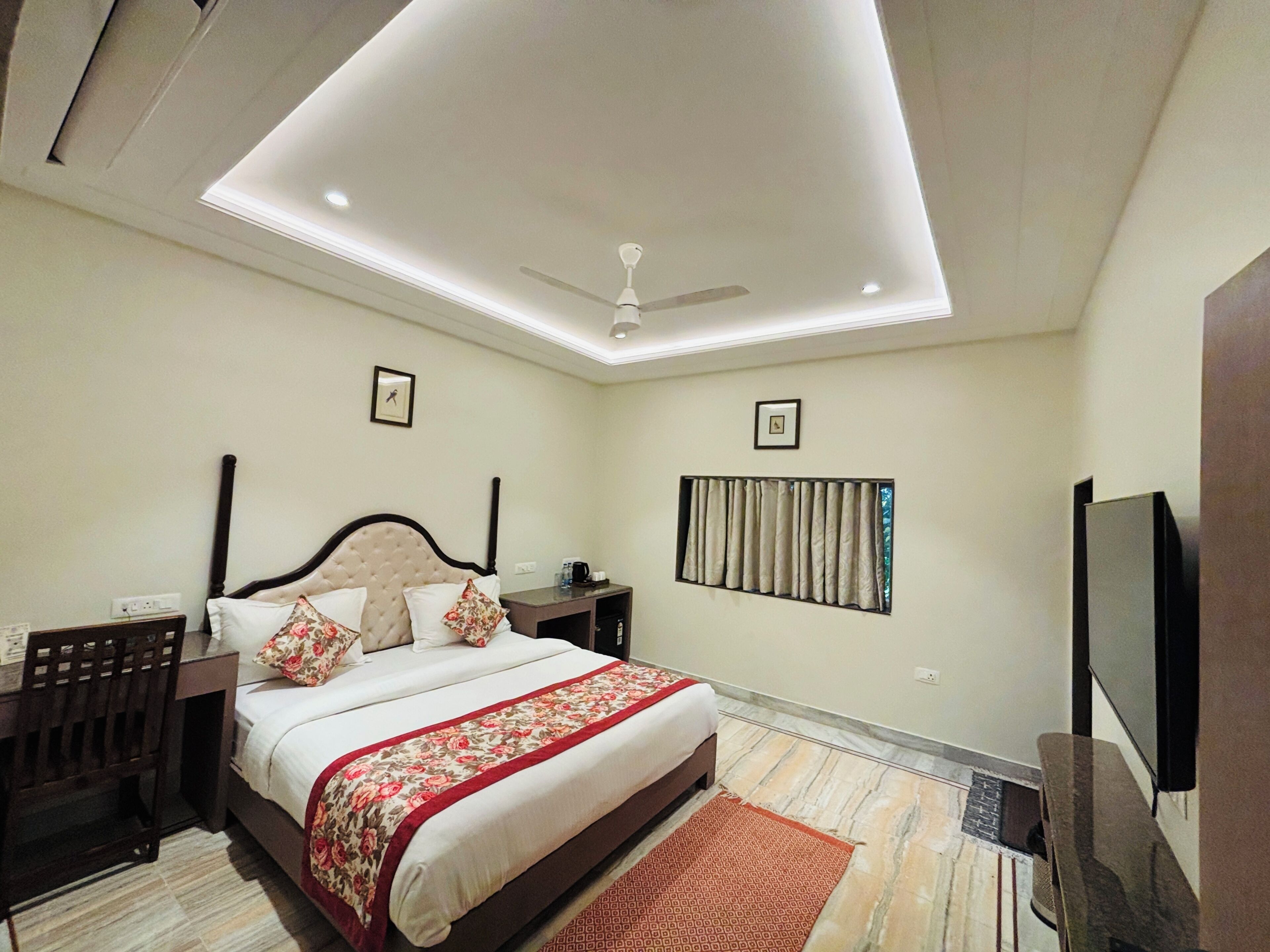 A bedroom with a bed, nightstands, a ceiling fan, a TV, and a window with curtains.