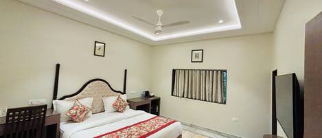 A bedroom with a bed, nightstands, a ceiling fan, a TV, and a window with curtains.