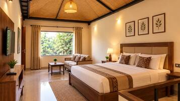 A hotel room with a large bed, a sofa, a desk, and a window with a view of trees.