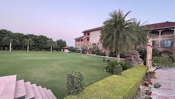A courtyard with a well-maintained lawn, a palm tree, and a building with a balcony.