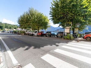 Une rue bordée de voitures garées et un passage piéton.
