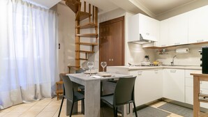 A modern kitchen with white cabinets, a wooden staircase, and a dining area with a table and chairs. - A Due Passi dal Lago (Tremezzina)
