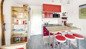 A compact kitchen with a wooden table, red bar stools, a microwave, and a sink.
