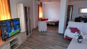 A modern living room with a television, a wooden cabinet, a dining area, and a bedroom with a bed and a nightstand. - Penthouse first line poniente beach. Elche Park. (Benidorm)