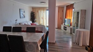 A hotel room with a dining area, a bed, a TV, and a view of the outside. - Penthouse first line poniente beach. Elche Park. (Benidorm)