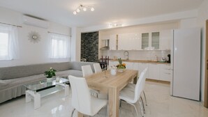 A modern kitchen with white cabinets, a wooden dining table, and a glass coffee table.