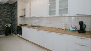 A modern kitchen with white cabinets, a wooden countertop, and a built-in stove.