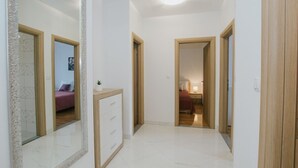 A hallway with a large mirror, wooden doors, and a small cabinet.