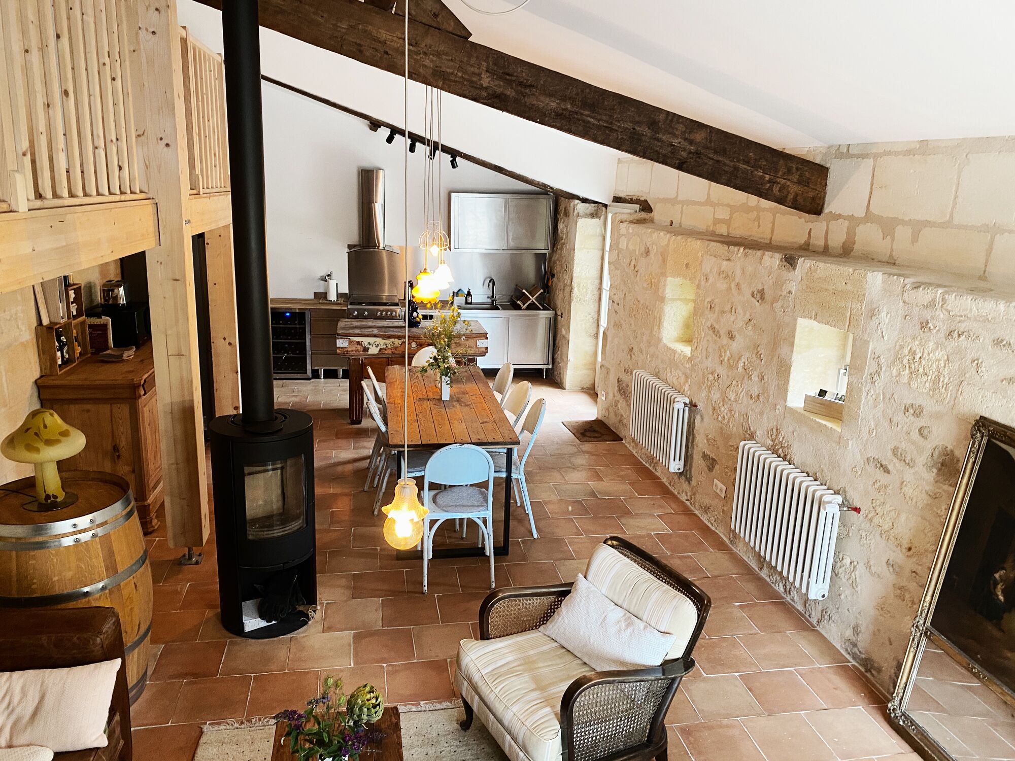 Un intérieur rustique avec une table à manger en bois, des chaises, un canapé, une cheminée et un coin cuisine.