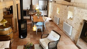 A rustic interior with a wooden dining table, chairs, a sofa, a fireplace, and a kitchen area. - La CLOCHETTE / La MAISONNETTE, La MAISONNETTE (Lugon-et-l'Île-du-Carnay)