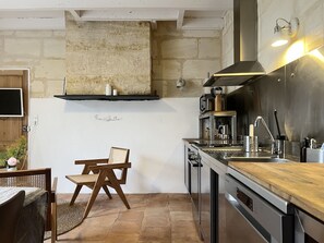 A modern kitchen with a wooden chair, a built-in stove, and a wall-mounted shelf.