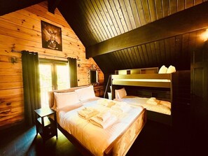 Une chambre confortable dans un chalet en bois, avec un lit superposé, une table de chevet et une fenêtre avec des rideaux.