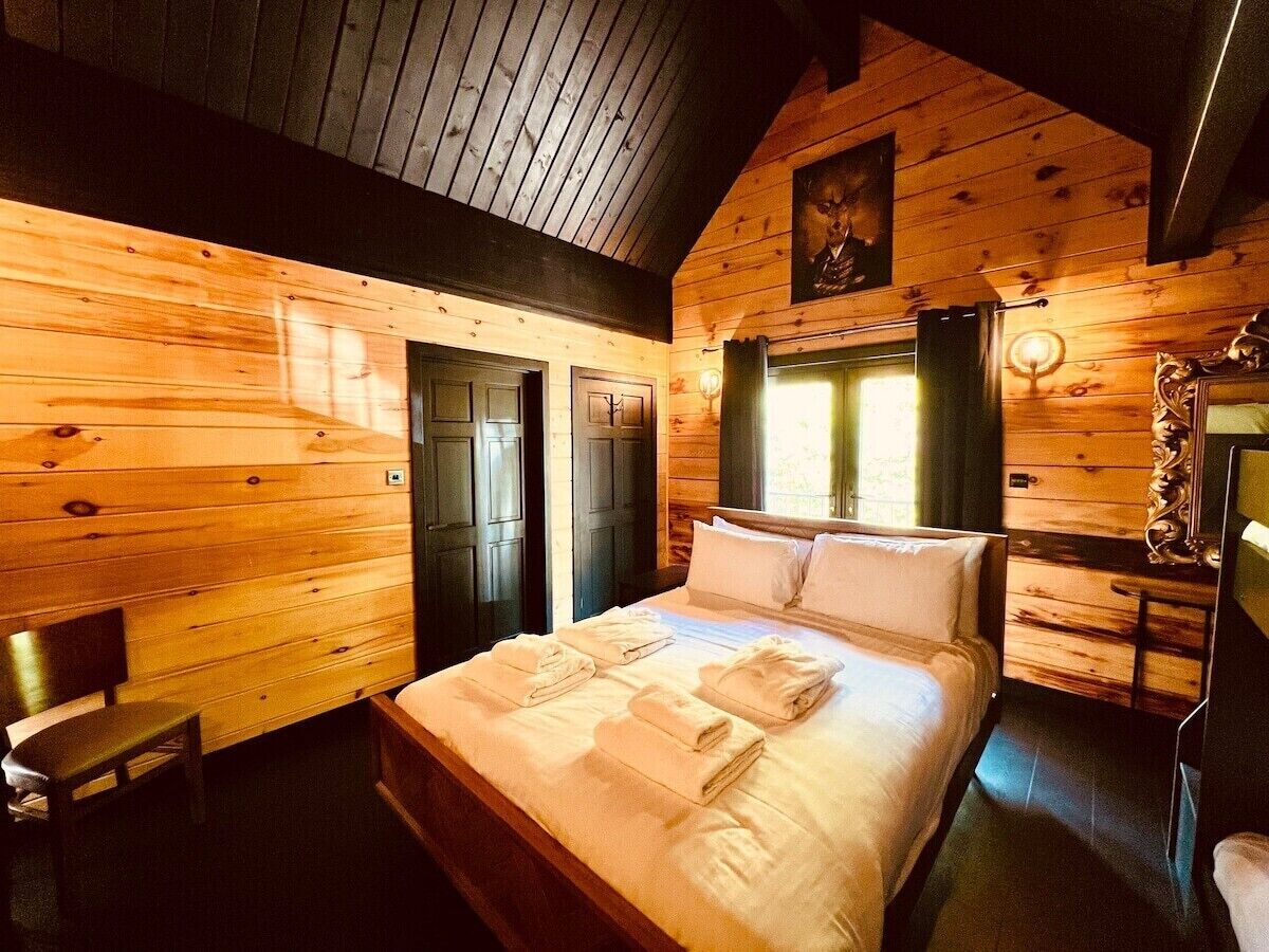 Una habitación tipo cabaña de madera con una cama, una silla y un escritorio.