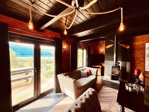 A cozy living room with a sofa, a fireplace, and large windows overlooking a scenic view.