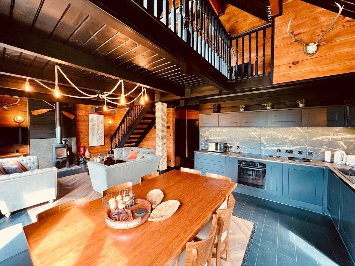 Een moderne keuken met blauwe kastjes, een houten eettafel en een trap naar een hoger niveau.