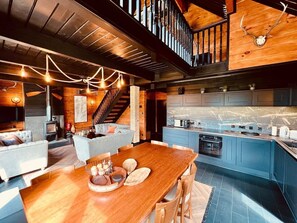 Une cuisine moderne avec des meubles de rangement bleus, une table à manger en bois et un escalier menant à un niveau supérieur.