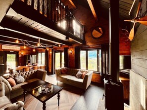 Un intérieur de chalet chaleureux avec une cheminée, des murs en bois et un coin repas.