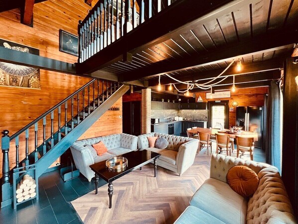 A spacious living area with a large sofa, a coffee table, and a staircase leading to an upper level.