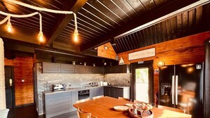 A modern kitchen with a large island, wooden chairs, and a dining table.
