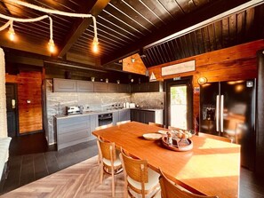 A modern kitchen with a large island, wooden chairs, and a dining table.