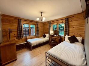 Une chambre de style cabane avec deux lits simples, un bureau en bois, une chaise et une commode.