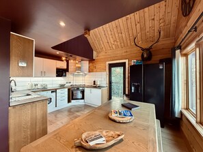 Eine moderne Küche mit Holzausstattung, einer zentralen Kochinsel und einem schwarzen Kühlschrank.