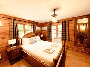 Un dormitorio con paneles de madera, una cama, mesitas de noche y un espejo.