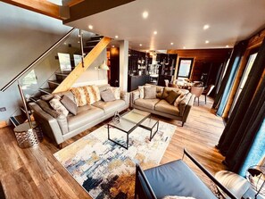 Un salon moderne avec un grand canapé d’angle, une table basse et un escalier.