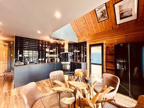 Una cocina moderna con una isla central, sillas de madera y una mesa de comedor.