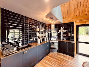 Een moderne keuken met een zwart betegelde spatwand, houten keukenkastjes en een inbouwoven.